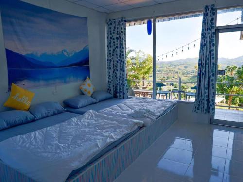 a large bed in a room with a large window at ภูม่านหมอก เขาค้อ in Ban Khao Ya Nua