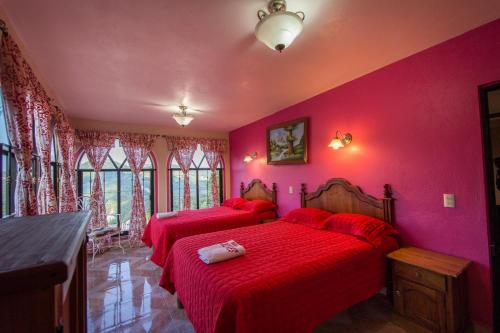 2 camas en una habitación con paredes y ventanas de color rosa en Hotel Dolores, en Xilitla