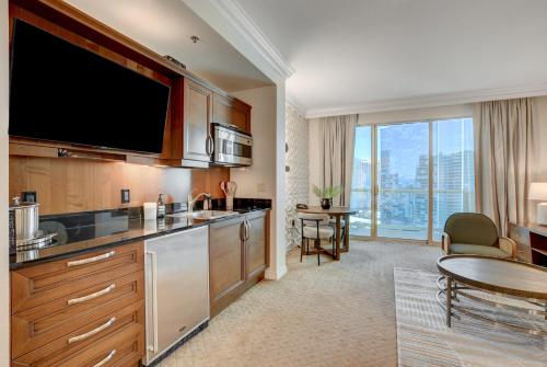 a kitchen with a large flat screen tv and a table at Jewel Suite w/balcony MGM SIGNATURE * 23rd FLOOR* STRIP VIEW in Las Vegas