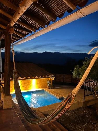 a hammock on a patio with a swimming pool at Casa Castañeto Barichara in Barichara