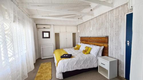 a bedroom with a bed with yellow pillows on it at Ocean Crest Villa in Cintsa Mouth West