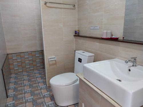 La salle de bains est pourvue de toilettes blanches et d'un lavabo. dans l'établissement พลอยไพลินPLOYPAILIN, à Pai