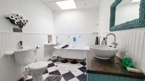 a bathroom with a tub and a toilet and a sink at Ocean Crest Villa in Cintsa Mouth West