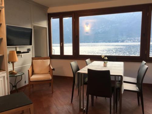 ein Esszimmer mit einem Tisch und Stühlen sowie einem großen Fenster in der Unterkunft Beautiful Villa with Private Access to the Lake. in Limonta