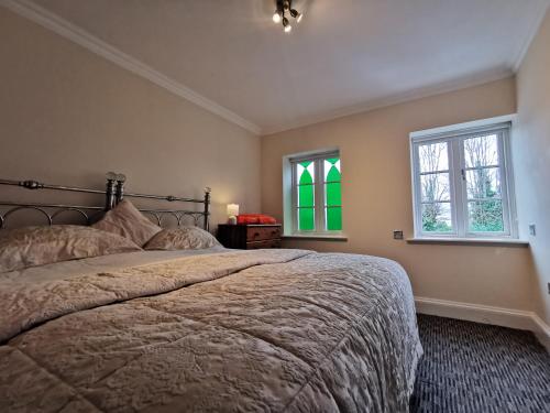 a bedroom with a large bed and two windows at Castle Retreats Nest & Crown in Torquay