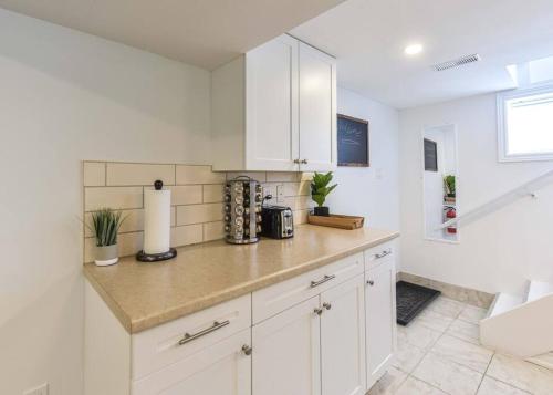 a kitchen with white cabinets and a counter top at Hidden Basement Gem: Cozy Comfort & Outdoor Fun in Barrie