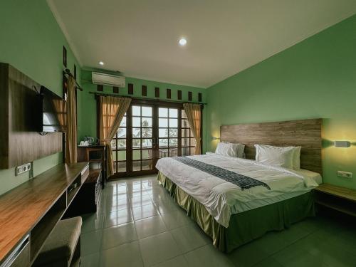 a bedroom with a large bed and green walls at VILLA IPSA in Munduk