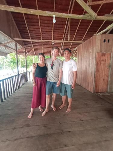 a group of three people standing on a bridge at Tanjung Kalemo Resort in Batudaka