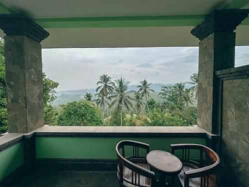 a balcony with two chairs and a view of palm trees at VILLA IPSA in Munduk