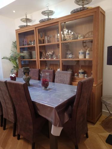 a dining room table with chairs and a cabinet with dishes at Appartement 3 chambres Centre Vilvoorde Bruxelles BrusselsAirport Expo NATO Anvers Wifi Free Parking in Vilvoorde