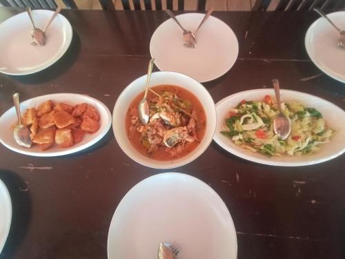 a table with white plates of food on it at Tanjung Kalemo Resort in Batudaka