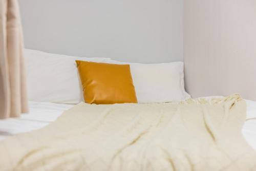 a white bed with a yellow pillow on it at Lavendar Duplex Apartment in Guangzhou