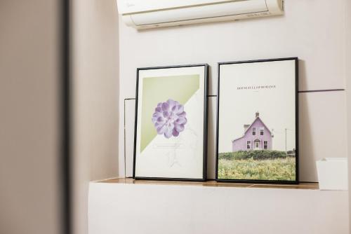 three picture frames on a shelf with a flower at Lavendar Duplex Apartment in Guangzhou