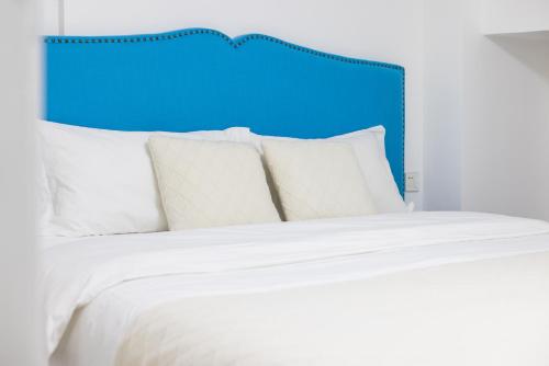 a bed with white pillows and a blue headboard at Lavendar Duplex Apartment in Guangzhou