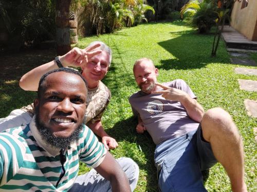 a group of three men sitting on the grass at TGS Homestay in Kampala