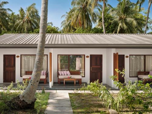 a guest house with a patio and palm trees at Villa Park Sun Island Resort in Maamigili