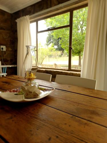 Saffier river cottage Farmstay في Lady Grey: طاولة عليها صحن و مزهرية زجاجية