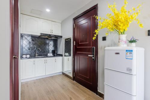 a kitchen with white cabinets and a refrigerator at Lavender Apartment in Guangzhou
