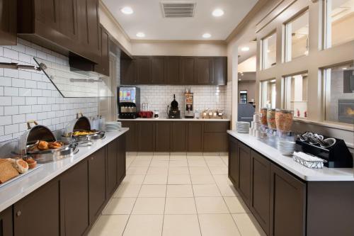 a large kitchen with brown cabinets and white tile floors at Residence Inn by Marriott Rogers in Rogers