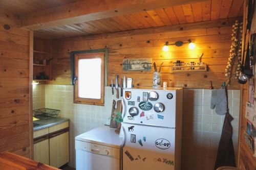 a kitchen with a white refrigerator and wooden walls at Cozy chalet Montana in Kopaonik