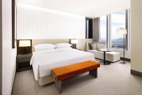 a bedroom with a large white bed and a chair at Hotel Onoma Daejeon, Autograph Collection in Daejeon