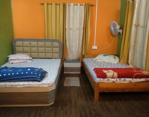 two beds in a room with orange walls at Karma Homestay by StayApart in Aritar