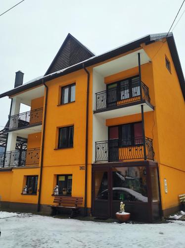 a yellow building with balconies on the side of it at Agroturystyka u Zosi in Żegiestów