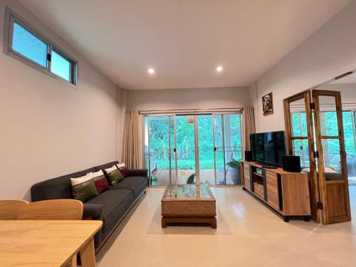 - un salon avec un canapé et une télévision dans l'établissement Creek Cottage Chaeson, à Ban Mun Thung