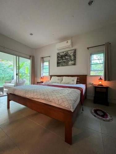 - une chambre avec un grand lit dans une pièce dotée de fenêtres dans l'établissement Creek Cottage Chaeson, à Ban Mun Thung