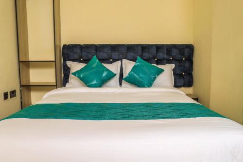 a bedroom with a large bed with green and white pillows at Hidden Treasure Lodge Chuka in Chuka