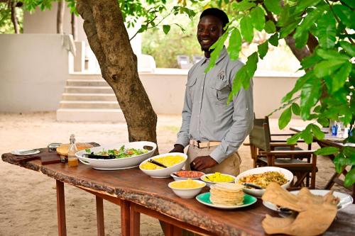 a man standing in front of a table of food at Msandile River Lodge in Kakumbi