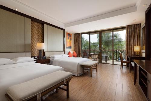 a hotel room with two beds and a balcony at Sheraton Shenzhou Peninsula Resort in Wanning