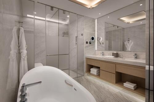 a bathroom with a tub and a large mirror at Wyndham Shaoxing Keqiao in Shaoxing