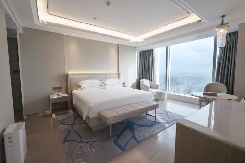 a bedroom with a white bed and a large window at Wyndham Shaoxing Keqiao in Shaoxing