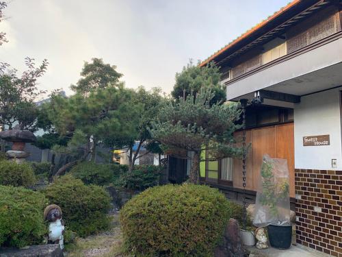 ein Gebäude mit einem Garten mit Bäumen und Sträuchern in der Unterkunft Guesthouse Hope in Hashima