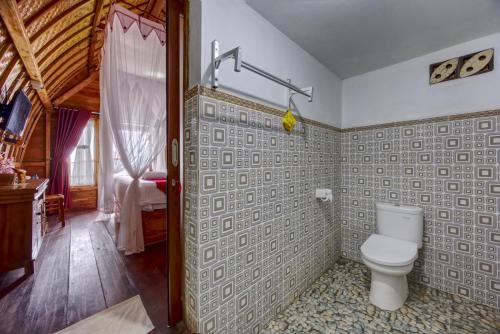 a bathroom with a toilet and a bedroom at Santen Beach Bungalows in Nusa Penida