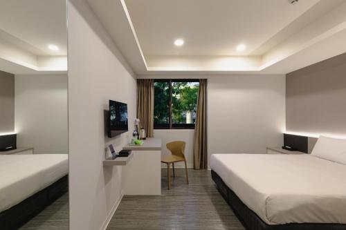 a hotel room with two beds and a desk at Kiwi Express Hotel - Zhongqing in Taichung