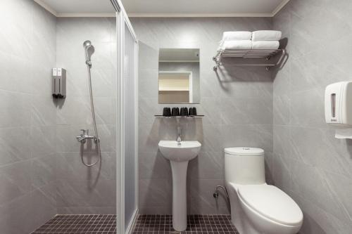 ein Bad mit einer Dusche, einem WC und einem Waschbecken in der Unterkunft Kiwi Express Hotel - Zhongqing in Taichung