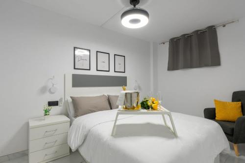 a white bedroom with a white bed and a table at THE WHITE CORNER BY HOMESTAYGRANCANARIA in San Bartolomé de Tirajana