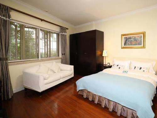 Ladoll Service Apartments في شانغهاي: غرفة نوم بسرير كبير واريكة بيضاء
