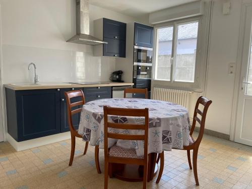 une cuisine avec une table, des chaises et des armoires bleues dans l'établissement Maison gîte 2/4 P baie du mont, à Pontorson