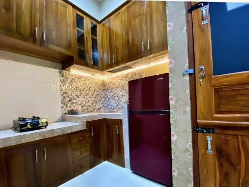 a kitchen with wooden cabinets and a red refrigerator at DMoon Villa in Yogyakarta