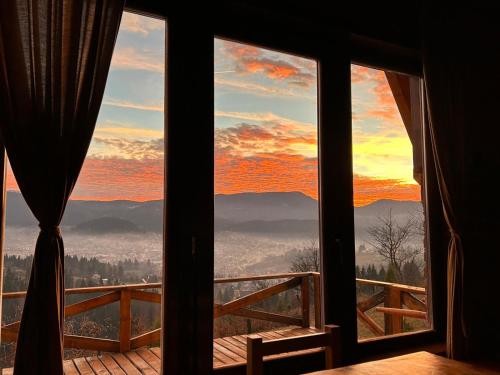 a room with a view of a sunset seen through windows at Vikendica Tromedja Pale in Pale