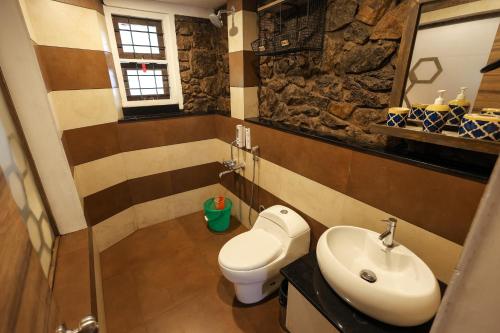 a bathroom with a toilet and a sink at The Preserve Stone House Bungalow in Meppādi