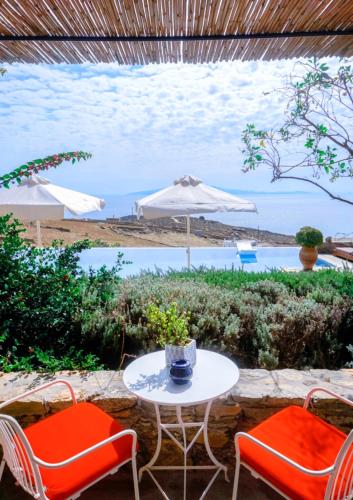 a table and two chairs and an umbrella and the ocean at VILLA NAUTILIA - Luxury Suites and Cottages in Kalafatis