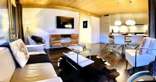 a living room with white furniture and a kitchen at Chalet CARVE - Apartments EIGER, MOENCH and JUNGFRAU in Grindelwald