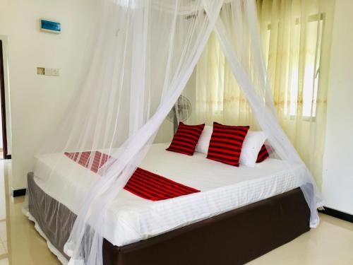 a bedroom with a bed with a mosquito net at Meyola Guest house in Weligama