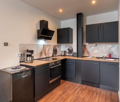 a kitchen with black cabinets and wooden floors at Ferienwohnungen An den SchwabachAuen - Keine Monteure in Eckental