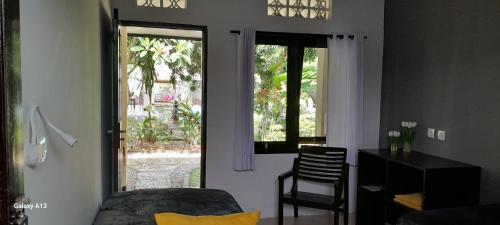a room with a bed and a desk and a window at Indah Homestay and Cooking classes in Senggigi