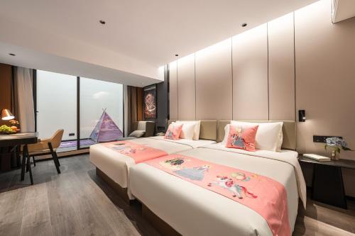 廈門市にあるAtour Hotel Xiamen Gaoqi Airport Chenggong Avenueのベッド2台とデスクが備わるホテルルームです。
